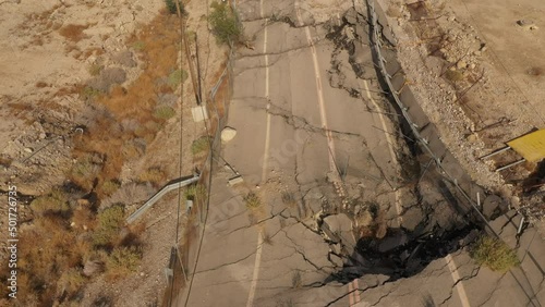 Tilted aerial view of destroyed road in Ein Gedi (Israel), where receding water levels lead to sinkholes and craters. Man-made ecological disaster along the Dead Sea coastline.
 photo