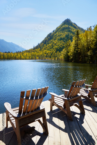 Beautiful autumn landscape. Wooden deck chairs on the lake shore. Concepts of travel and outdoor recreation.