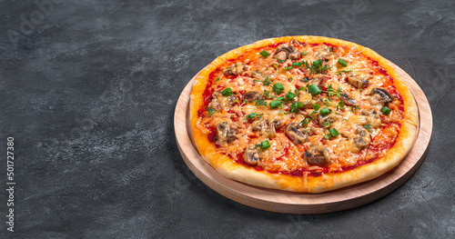 Pizza with mushrooms, tomatoes, cheese and herbs on a cutting board.