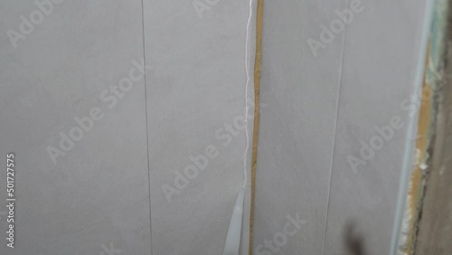 Worker man apply silicone glue to the wall with an applicator gun for gluing PVC panels to the wall