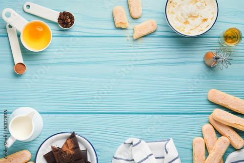 Tiramisu dessert. Ingredients for making dessert tiramisu. Cooking Italian food dessert Tiramisu with all necessary ingredients cocoa, coffee, mascarpone cheese on turquoise wooden background Top view