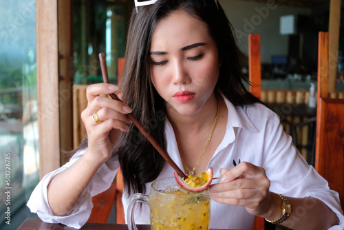 Young asian woman tasting passion fruit from juice