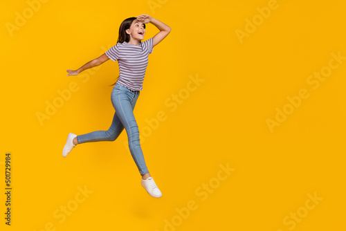 Full body profile side photo of young excited girl watch empty space go walk isolated over yellow color background