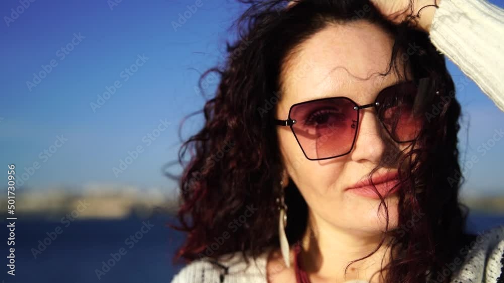 Portrait of a middle-aged woman with dark hair of European appearance, whose hair is developing against the sea. Portrait of a middle-aged woman with dark hair of European appearance, whose hair is developing against the sea.