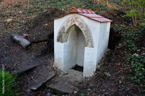 renovation of a well with repair of a roof made of burnt tiles. a small brick building with a goric appearance. digging the soil and repairing the facade, photo