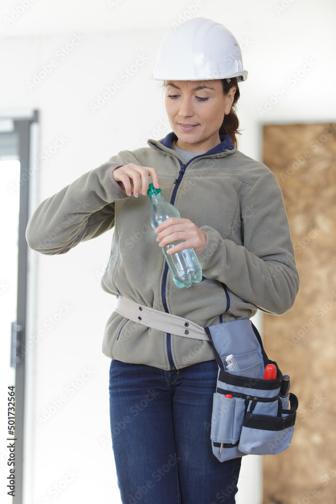 female construction worker opening water bottle to drink female construction worker opening water bottle to drink