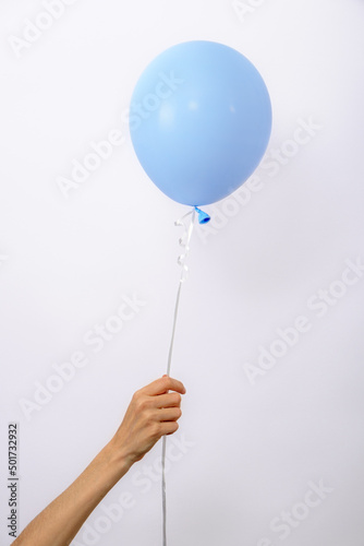 vertical one minimal blue balloon in hand on white background, copy space, element of decorations for birthday party, wedding, festival