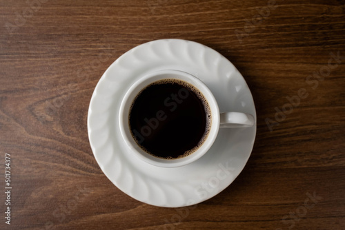 Dark coffee in white mug on wooden table..