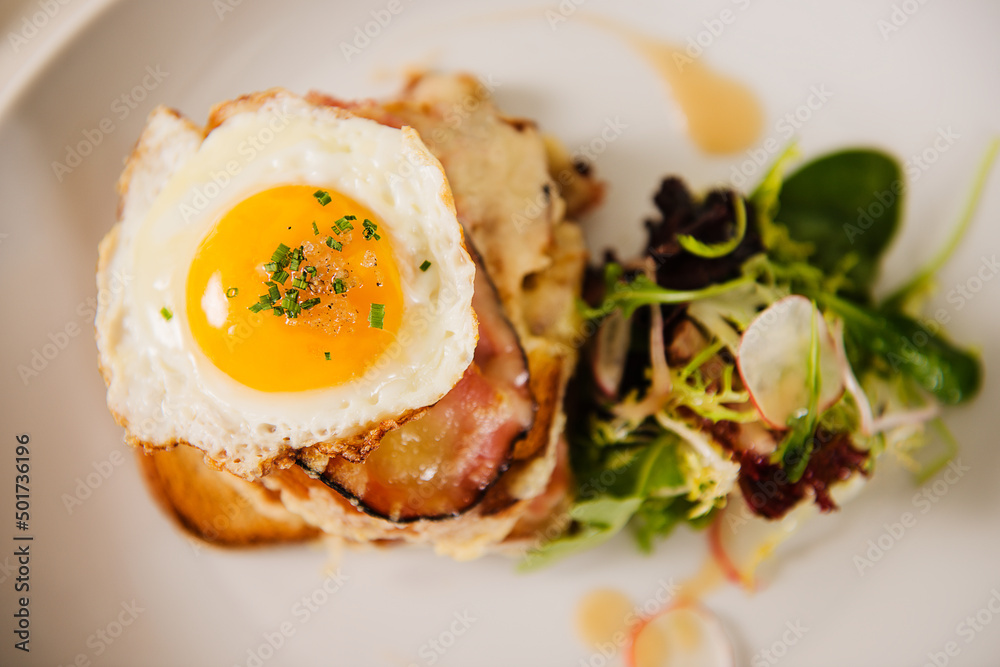 Croque Madame (toast topped with dry-cured ham, grilled cheese and a fried egg). Croque Madame (toast topped with dry-cured ham, grilled cheese and a fried egg).