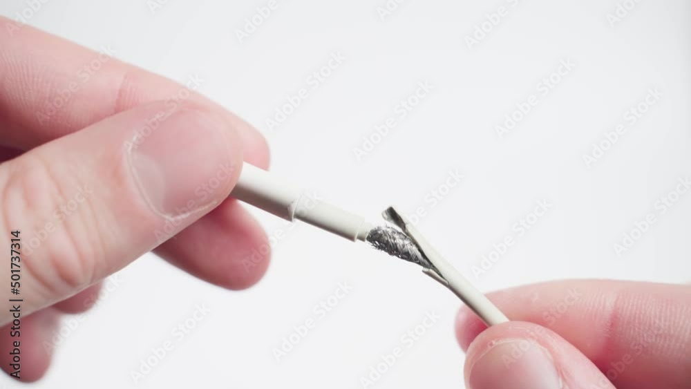 White lightning wire broken in hands on a white background close-up. Frayed charging cable.