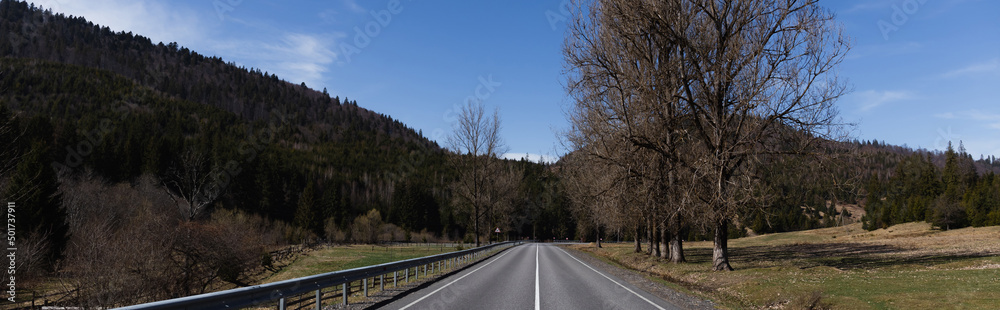 Fototapeta premium Empty road, mountains and trees with sky at background, banner.