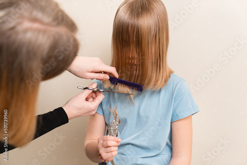 Mom cuts her daughter's wet hair. cutting hair at home. life hacks and rules of hair care. special combs and scissors for hairdressers.