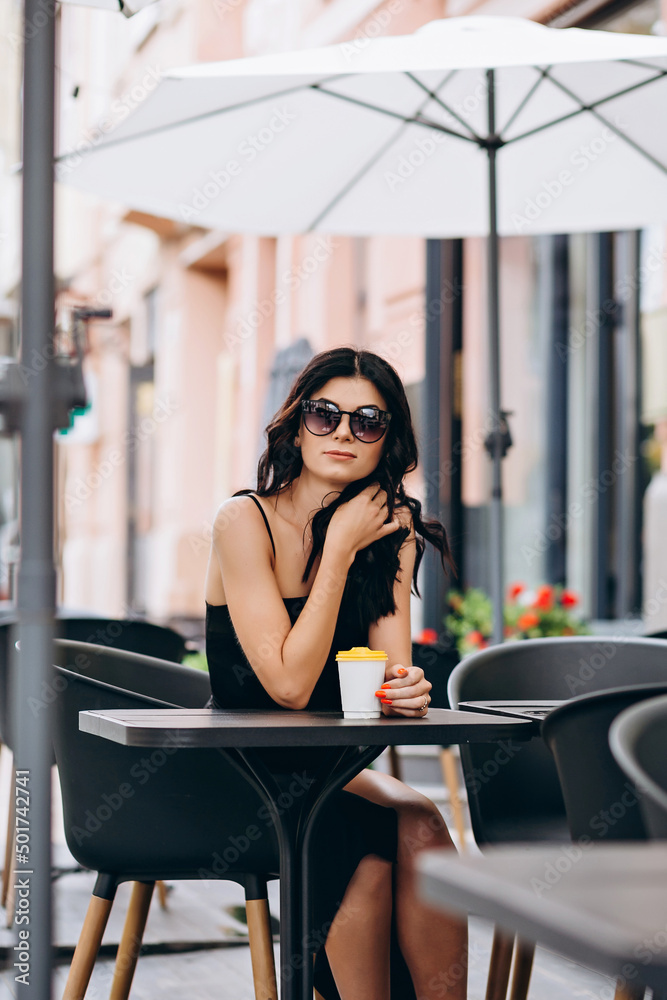 Young woman with coffee in a cafe on the street