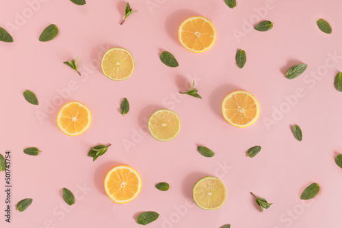 Summer pattern made of lemon and lime slices, and mint leaves on bright pink background. Minimal refreshment idea. Flat lay aesthetic.