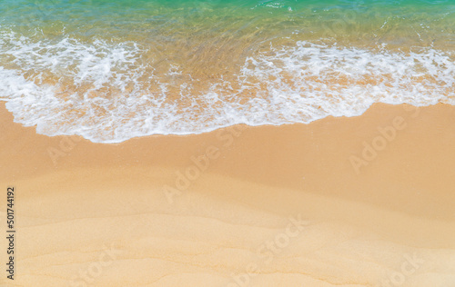 Sand beach seaside with white foamy and wave from blue sea, landscape seashore in summer season
