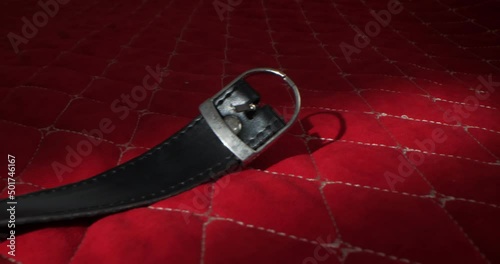 detailed, extreme close-up round gag on leather straps on a red blanket photo