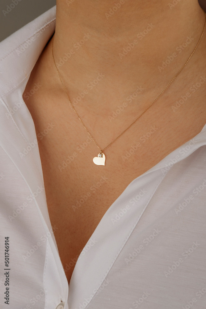 Black and gray A black-haired female model wearing a gray jacket and a white T-shirt jewels a gold necklace around her neck Black and gray A black-haired female model wearing a gray jacket and a white T-shirt jewels a gold necklace around her neck