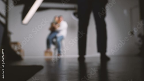 Photographer shooting family portrait in photography studio with flash strobe and lighting equipment.