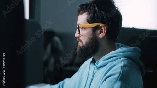 Web developer in glasses working on a computer in IT office