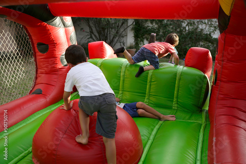 Boys playing in inflatable game. Childrens climbing on inflatable castle. Children\'s birthday. Fun in amusement park. Game for children. Childhood. Children\'s party.