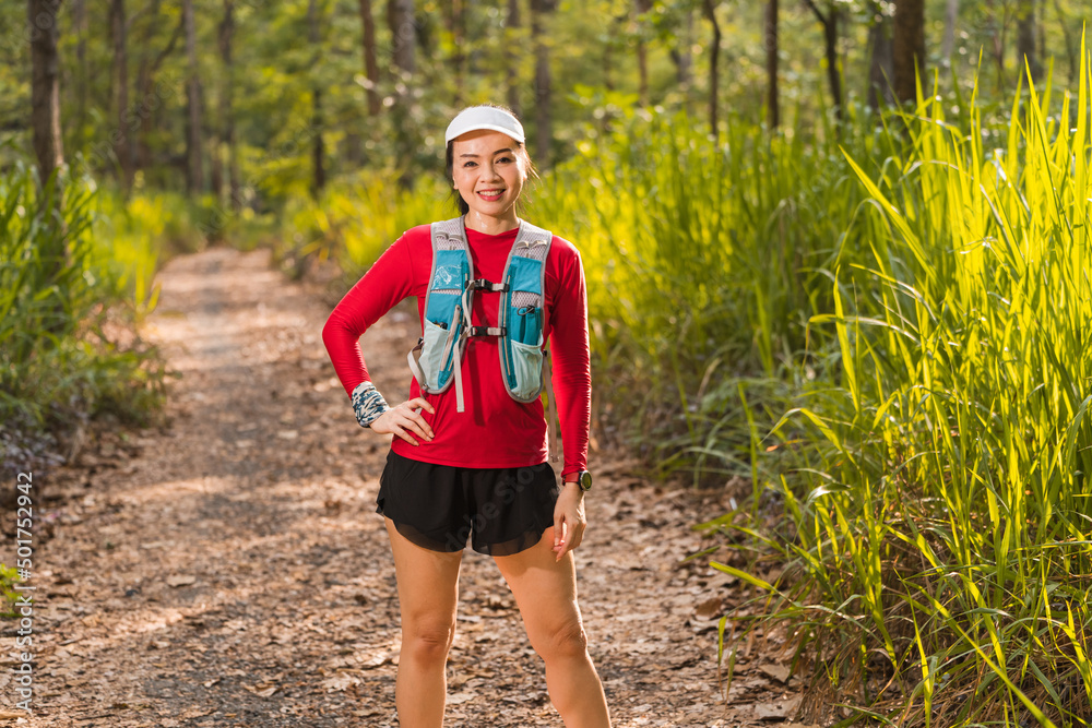 Portrait adult Asian woman trail runner with running vest doing trail running training in the forest park Portrait adult Asian woman trail runner with running vest doing trail running training in the forest park