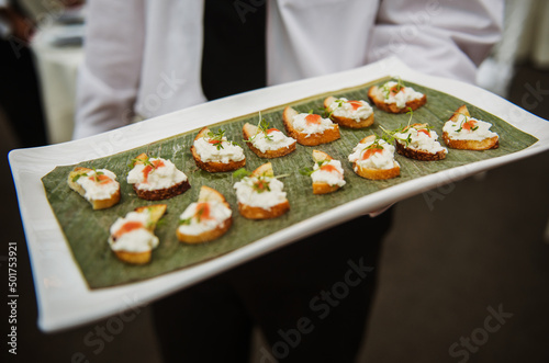 Waiter serving hors d'oeuvres of toast with cheese and herbs at an event.