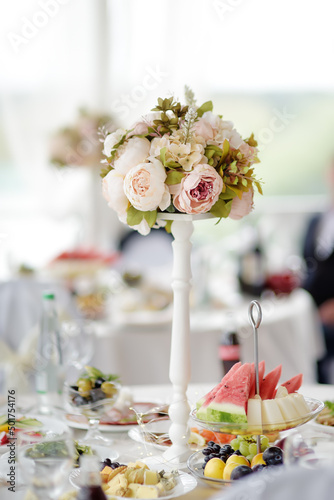 Beautiful table set for a party, wedding reception or festive event. Fruits and appetizers for event dinner. Stylish flowers bouquet.