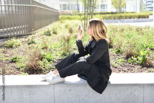 bellissima ragazza al parco che guarda il telefono e invia messaggi vocali photo