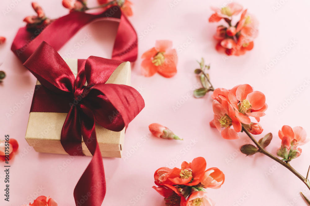 Happy Mothers day. Stylish gift box with flowers on pink background composition. Greeting card template. Craft gift with ribbon and red flowers. Women's day or birthday banner Happy Mothers day. Stylish gift box with flowers on pink background composition. Greeting card template. Craft gift with ribbon and red flowers. Women's day or birthday banner