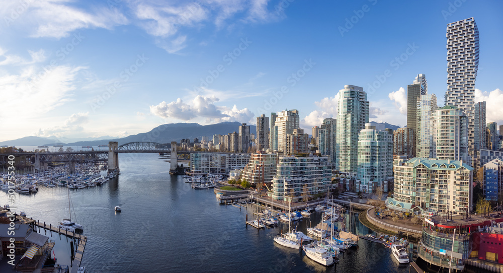 Fototapeta premium Panoramic Aerial View of Granville Island in False Creek with modern city skyline and mountains in background. Downtown Vancouver, British Columbia, Canada.