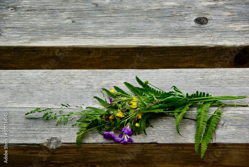 Small bouquet of picked swedish wild flowers lying on a wooden bench in summer. photo