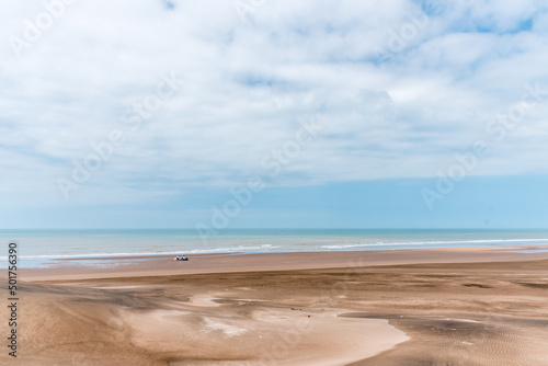 Landscape picture of the sands and dunes in front of the sea with some sky clouds. 