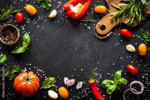 Food frame. Food cooking background on black stone table. Fresh vegetables, herbs and spices. Top view with copy space.