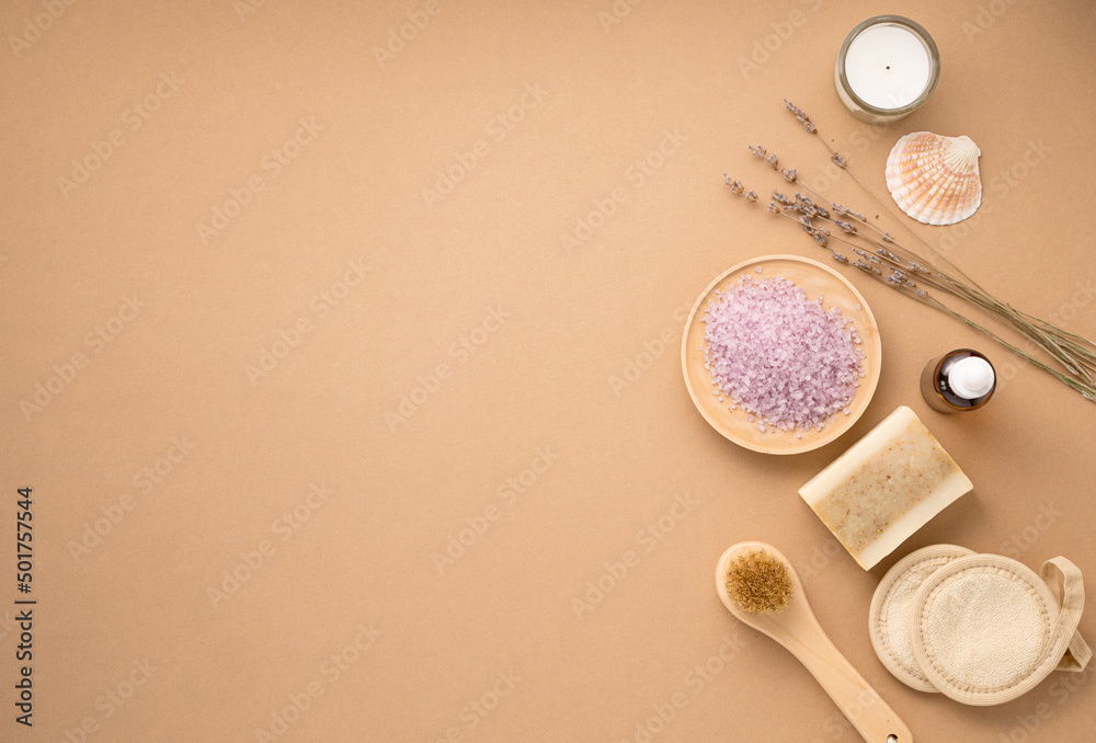 Organic sea salt for the body with dry lavender flowers, sponge, brush, soap and candle on a beige background. Skin care. The concept of a natural and eco-friendly spa product. Top view, copy space