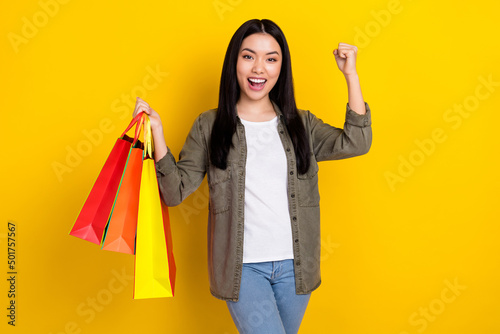 Photo of cool millennial brunette lady hold bags wear casual cloth isolated on yellow color background
