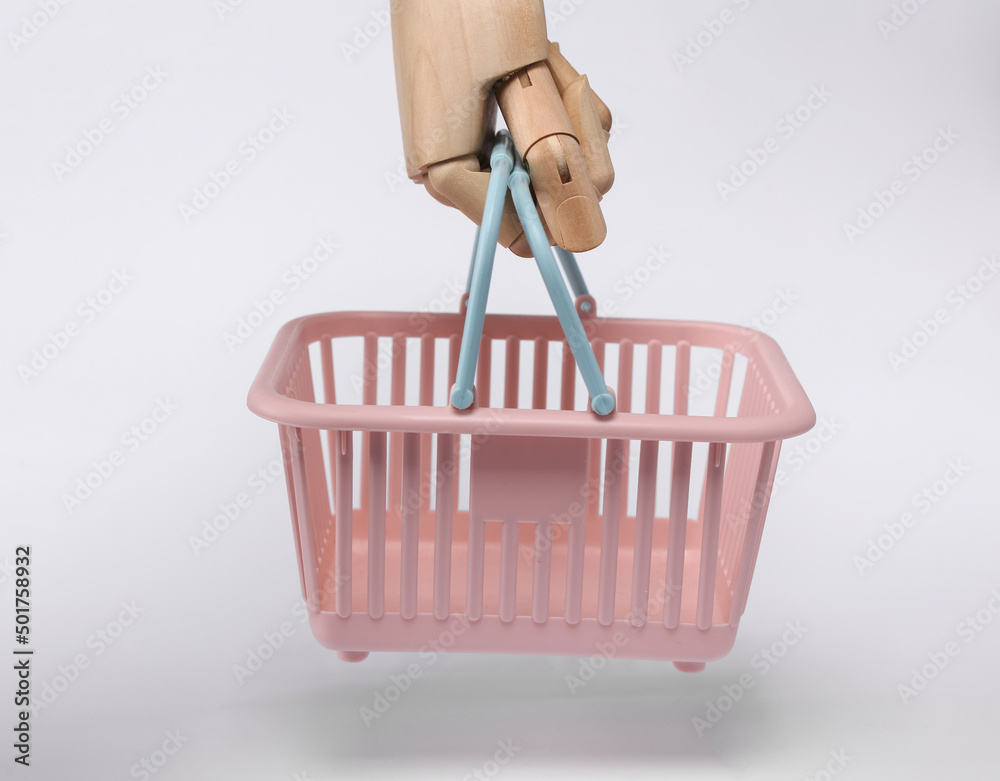 Fototapeta premium Wooden hand holding Plastic supermarket basket isolated on white background