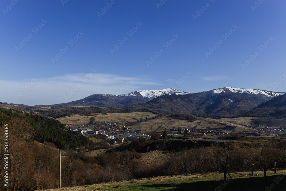 Village and mountains with blue sky at background.