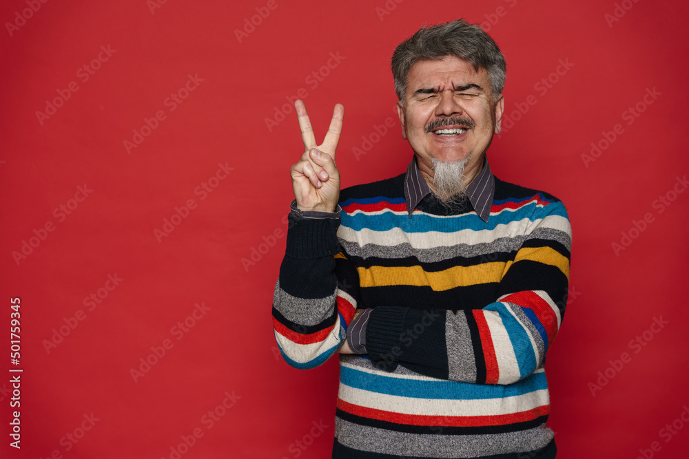 Mature man with grey beard showing peace sign and laughing Mature man with grey beard showing peace sign and laughing