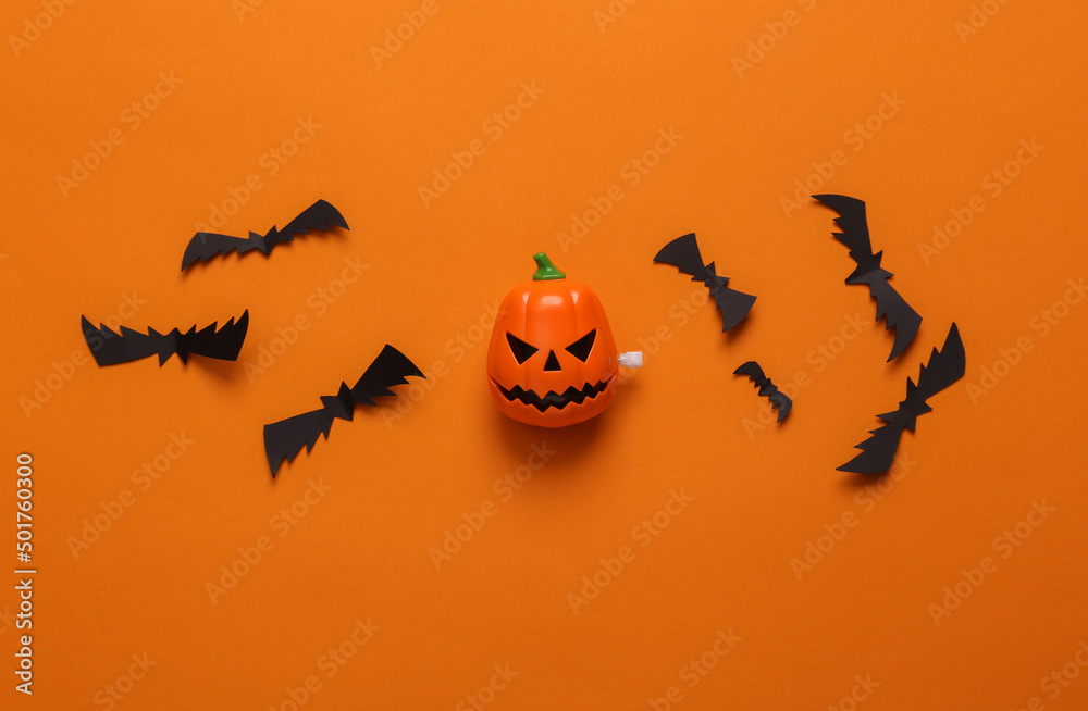 Halloween background with jack pumpkin head and bats on orange background. Top view. Flat lay