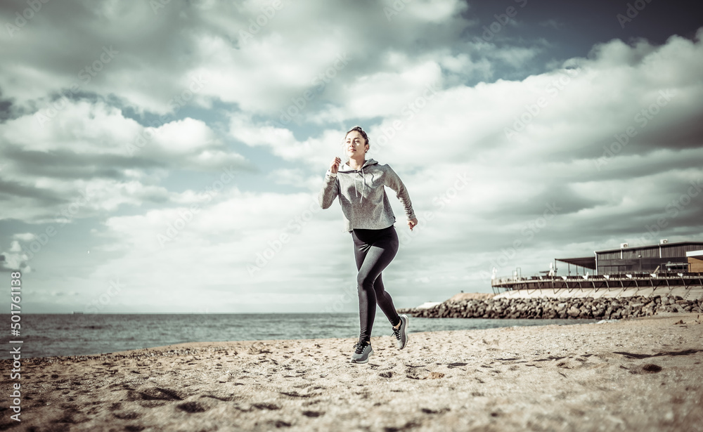 Sporty fit woman running on the beach on a bright sunny day