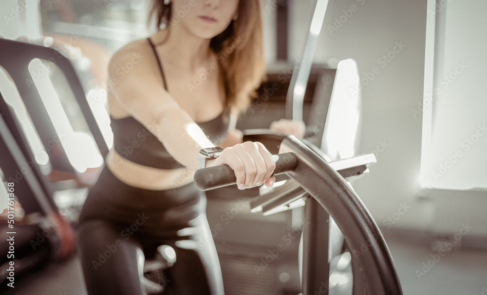 Fitness woman works out on air bike in modern gym. Fitness woman works out on air bike in modern gym.
