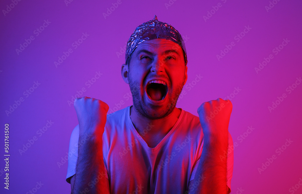 Emotional Bearded Man in foil hat in blue red neon light. - obrazy, fototapety, plakaty 
