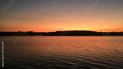 Beautiful sunset over lake Natural background with blue water and sky with yellow orange purple clouds, reflected in the lake. Breathtaking horizon panoramic view with setting sun.