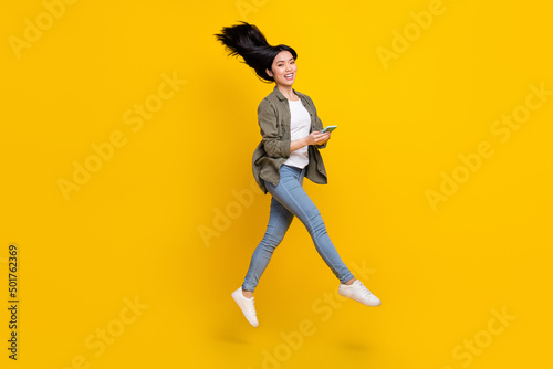 Full body of carefree lady jump use device chatting about eshop discounts isolated shine color background