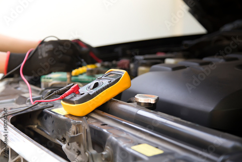 A technician is checking the car battery for availability. 