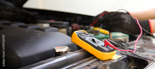 A technician is checking the car battery for availability.	