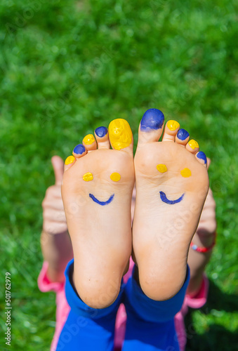 Child feet on the grass Ukrainian flag. Selective focus. © yanadjan