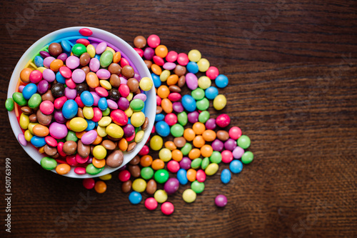 A lot of little tasty chocolate clored candies on wooden background