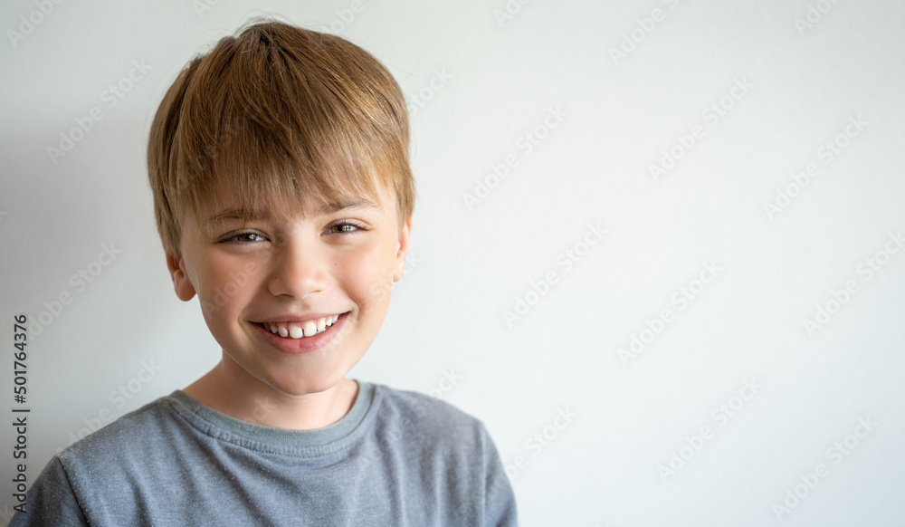 Portrait of smiling child, teenager in grey t-shirt looking at camera over white background. Positive mood. Portrait of smiling child, teenager in grey t-shirt looking at camera over white background. Positive mood.