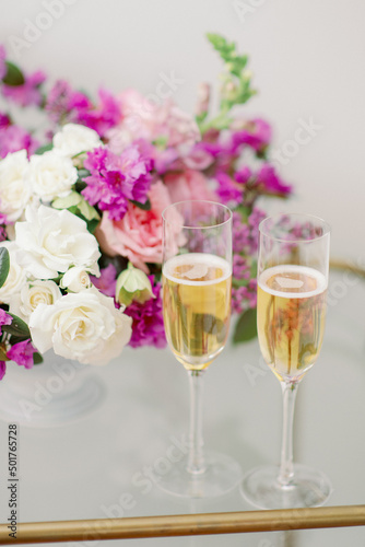 close up of two full champagne flutes with spring flowers behind